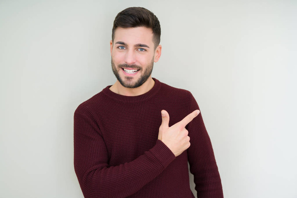 Fiatal jóképű férfi egy pulóvert visel felett vidám mosollyal az arcát mutatva a kéz és az ujjak, akár az oldalán arcán boldog és természetes kifejezés elszigetelt háttér - Fotó, kép