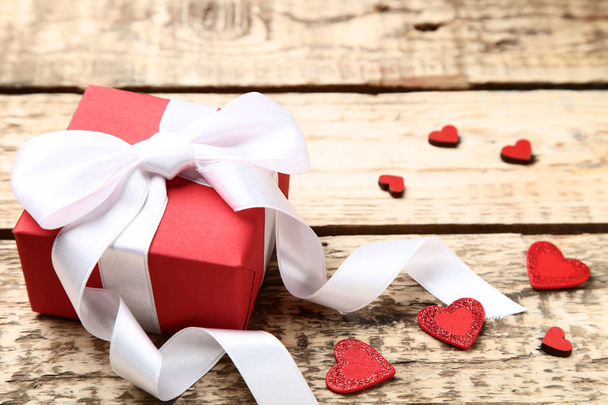 Gift box with ribbon bow and hearts on brown wooden table - Fotografie, Obrázek