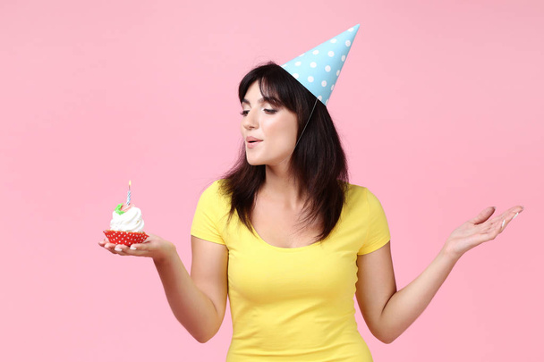 Young woman with birthday cupcake on pink background - Foto, immagini