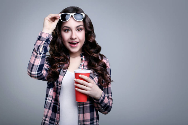 Young beautiful woman with paper cup on grey background - Фото, изображение