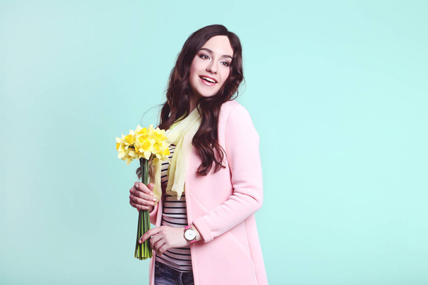 Beautiful woman in fashion clothes with narcissus flowers on mint background - Foto, Imagem