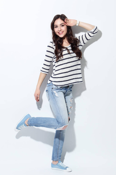 Beautiful woman in jeans and sweater on white background - Фото, изображение