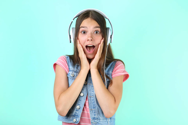 Young girl with headphones on mint background - 写真・画像