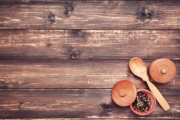 Colher de cozinha de madeira e tigela com tempero de pimenta na mesa marrom
 - Foto, Imagem