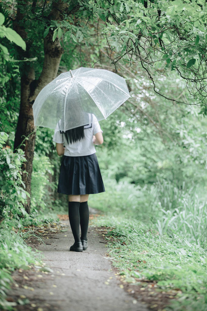 Portret Azjatyckie uczennice, chodzenie z parasol o charakter chodnik na deszcz - Zdjęcie, obraz
