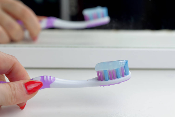浴室の白い棚の上のピンクの歯ブラシ、ミラー、朝ケア、歯のケア、女性を滑らせての健康に反映されます。 - 写真・画像