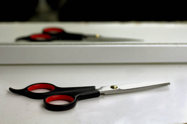Friseurwerkzeuge Schere für Friseur auf weißem Regal spiegelt sich im Spiegel - Foto, Bild