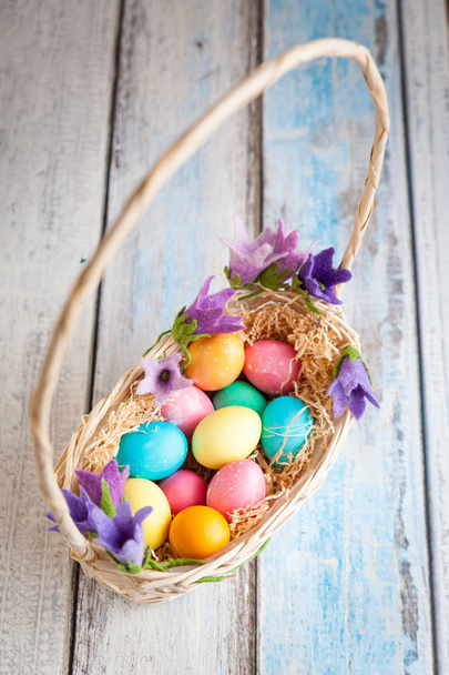 Velikonoční vajíčka v košíku na dřevěném stole - Fotografie, Obrázek