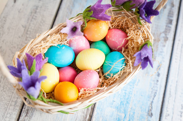 Easter eggs in a basket on a wooden table - Fotó, kép