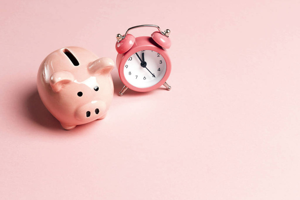 Piggy bank and classic alarm clock on pink background. Time to saving, money, banking concept.  Flat design, copy space for text. - Foto, immagini
