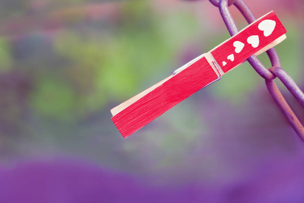 Red clothespin with hearts on the chain. The concept of strong love. beautiful blurred background. - Photo, image