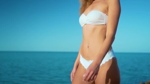 Sexy kobieta w białym bikini spaceru na plaży na słoneczny dzień. - Materiał filmowy, wideo