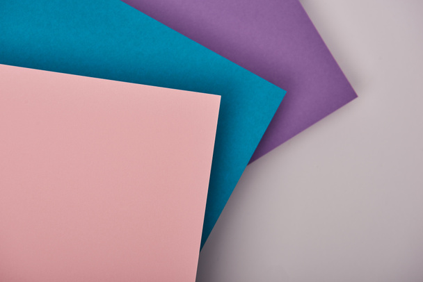 top view of blue, purple and pink paper sheets with copy space on white background - Фото, зображення