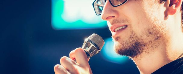 Young man on the stage is talking into a microphone, speech - Foto, Bild