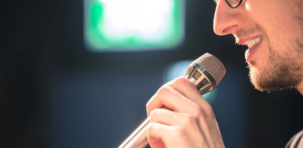 Young man on the stage is talking into a microphone, speech - Foto, Imagen