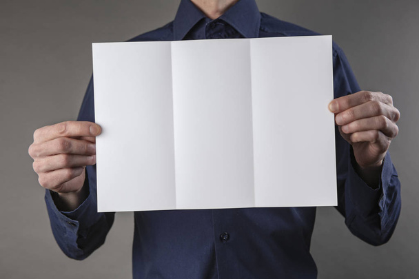 A man holding white booklet - Foto, imagen