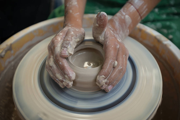 дитина виробляє кераміку на традиційному гончарному колесі
 - Фото, зображення