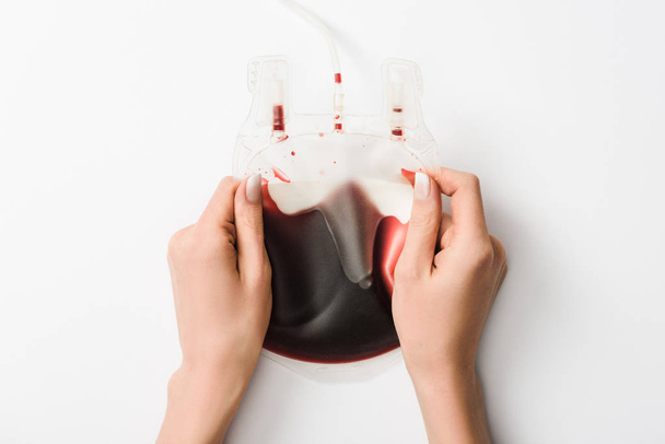 Partial view of woman holding drip with blood on white background, blood donation concept - Fotoğraf, Görsel