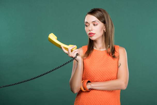 beautiful stylish woman holding retro telephone isolated on green - Zdjęcie, obraz