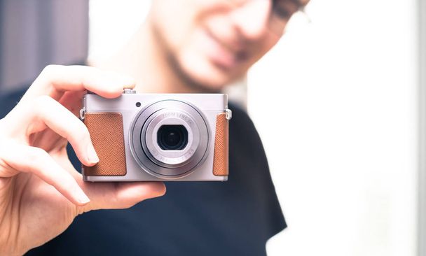 Young man with vintage camera smiles and takes a photo - Фото, изображение