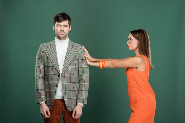 beautiful woman pushing handsome man in vintage clothes isolated on green - Photo, Image