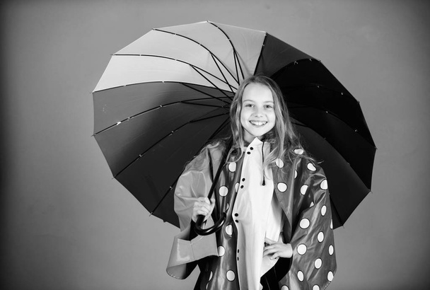 Kid girl happy hold colorful umbrella wear waterproof cloak. Enjoy rainy weather with proper garments. Waterproof accessories for children. Waterproof accessories make rainy day cheerful and pleasant - Photo, Image