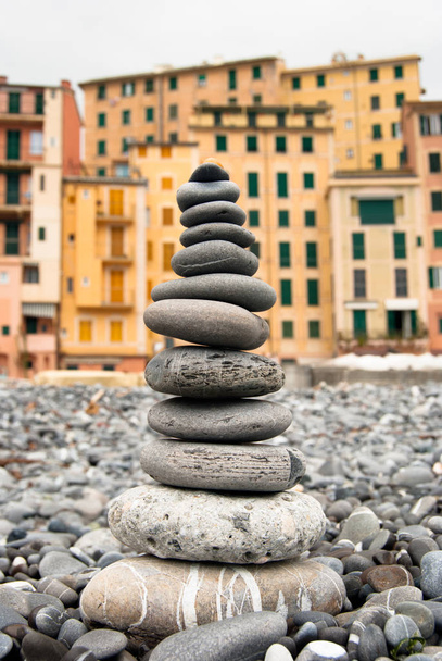Close- up of a pyramid of characteristic stones of  Camogli beach and colored houses as a background - Photo, Image