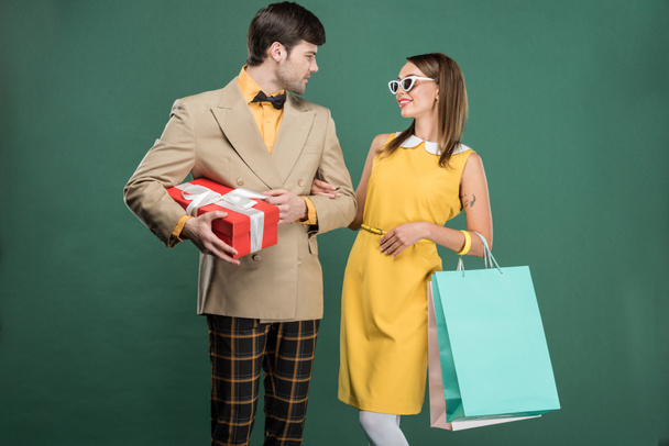 mooie paar in vintage kleding met boodschappentassen geïsoleerd op groen - Foto, afbeelding