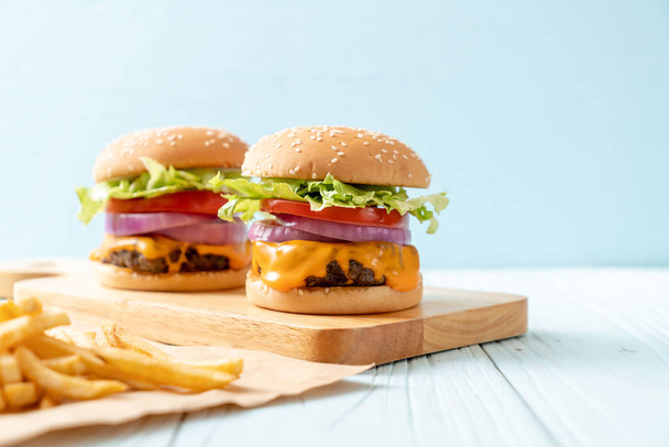 hamburguesa de carne fresca sabrosa con queso y papas fritas sobre fondo de madera
 - Foto, imagen