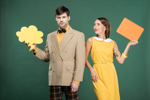 beautiful couple in vintage clothes holding speech bubble and thought bubble isolated on green - Photo, Image