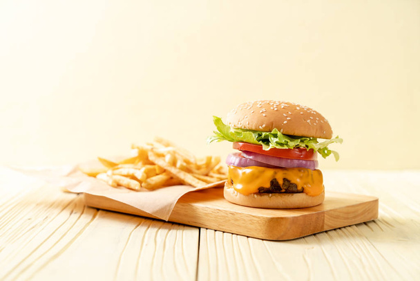friss, ízletes marha burger, sajttal és sült krumpli a fa háttér - Fotó, kép