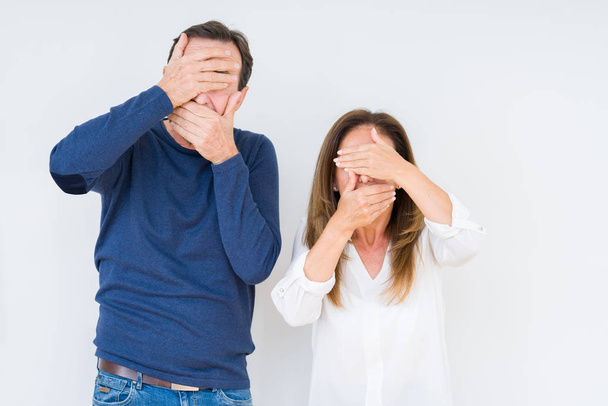 Beautiful middle age couple in love over isolated background Covering eyes and mouth with hands, surprised and shocked. Hiding emotion - Foto, immagini
