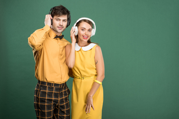 beautiful happy couple in vintage clothes with headphones isolated on green - Zdjęcie, obraz