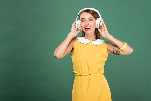piękna kobieta szczęśliwa w żółtej sukience i słuchawki na zielony z miejsca kopiowania tle - Zdjęcie, obraz