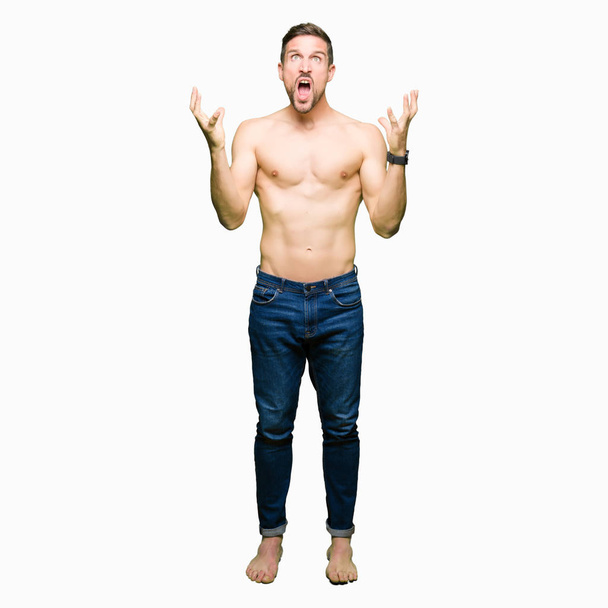 Handsome shirtless man showing nude chest crazy and mad shouting and yelling with aggressive expression and arms raised. Frustration concept. - Photo, Image