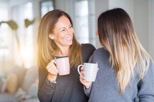 Beautiful family of mother and daughter together drinking a cup of coffee at home - Photo, Image