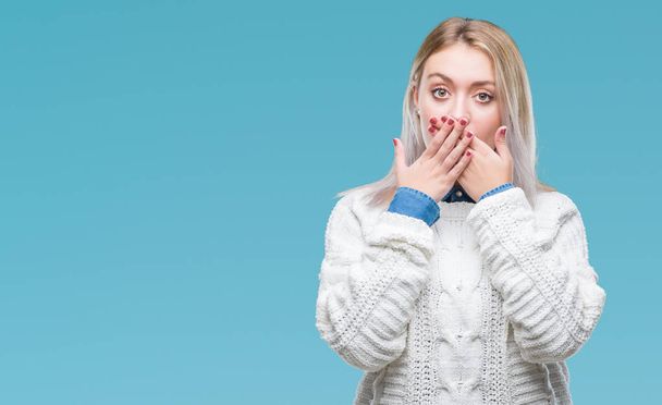 Mladá blond žena nosí zimní svetr izolované pozadí šokován, pokrývající ústa rukama za chybu. Tajné koncept. - Fotografie, Obrázek