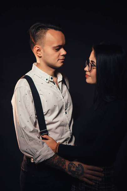 Couple in fashionable clothes on a dark background with smoke. - Фото, изображение