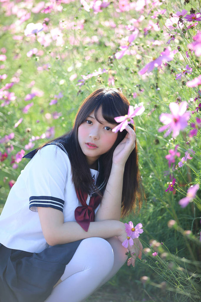 コスモスの花と座っている日本の学校女子制服の肖像画  - 写真・画像