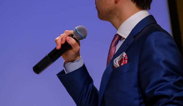 Man speaks, holding a microphone - 写真・画像