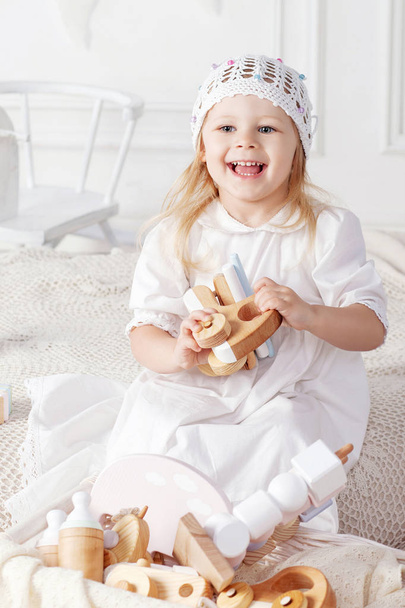 Smiling child girl playing with a wooden toys. Little cute girl with  natural toys.   - Foto, imagen