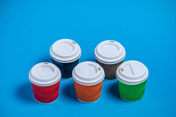 барвисті картонні чашки для одноразового використання на синьому фоні
 - Фото, зображення