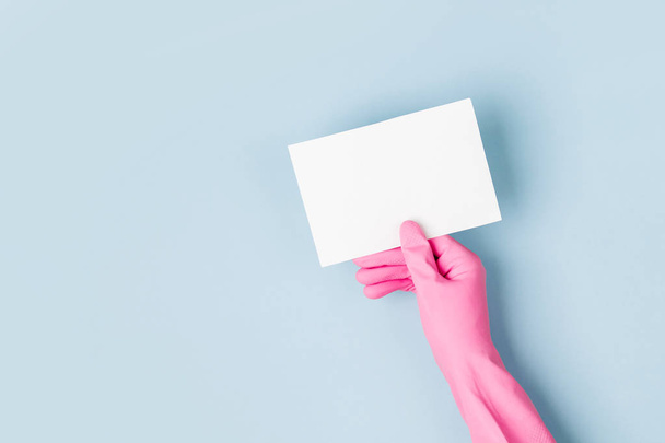Hands in pink gloves hold empty card. Cleaning or housekeeping concept background. Copy space. Flat lay, Top view. - Foto, Imagen