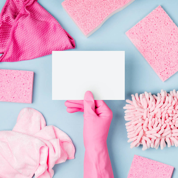 Hands in pink gloves hold empty card. Cleaning or housekeeping concept background. Copy space. Flat lay, Top view. - Фото, изображение