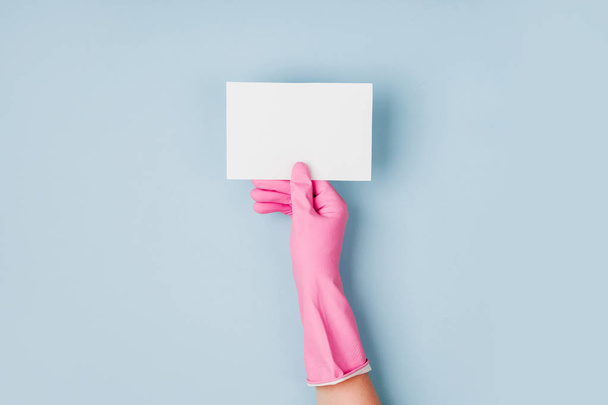 Hands in pink gloves hold empty card. Cleaning or housekeeping concept background. Copy space. Flat lay, Top view. - Foto, afbeelding