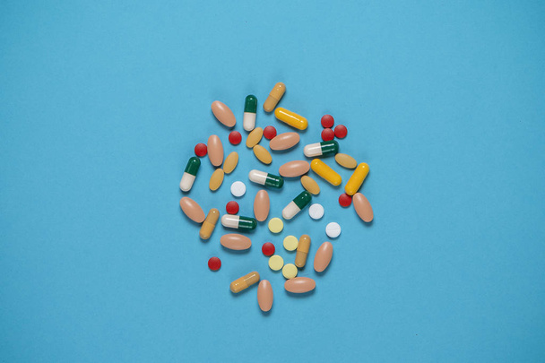 pílulas multicoloridas espalhadas em um fundo azul com um lugar para espaço de cópia
 - Foto, Imagem