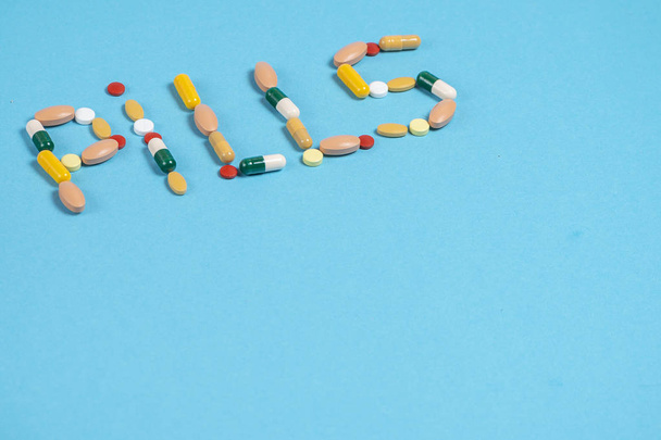 word pills is laid out from colorful pills on a blue background with a place for copy space - Valokuva, kuva