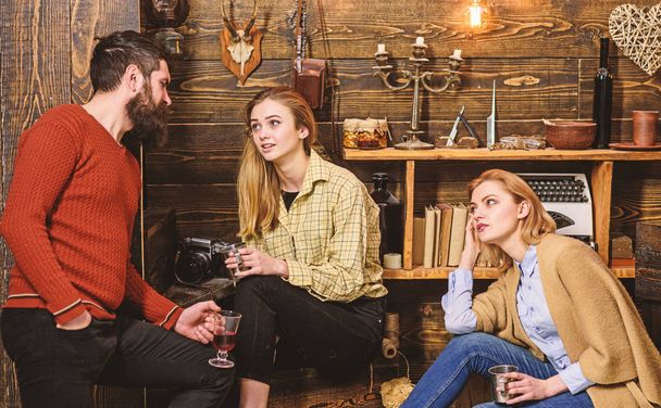 Friends, family spend pleasant evening, interior background. Friends having great day at gamekeepers house. Sincere conversation concept. Girls and man on relaxed faces hold metallic mugs, talking - Fotó, kép