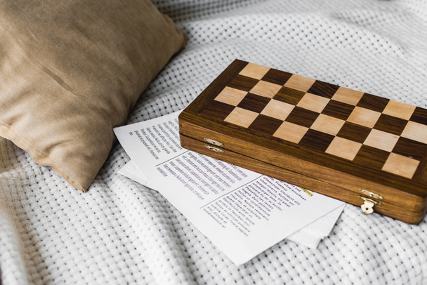 wooden chess board near newspaper on sofa  - Photo, Image