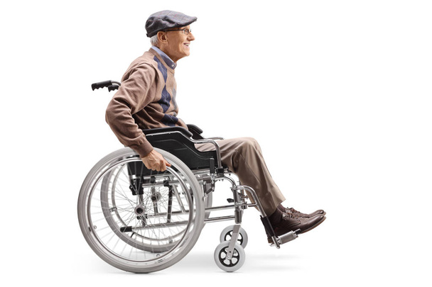 Full length profile shot of a senior man manually riding a wheelchair isolated on white background - Фото, изображение